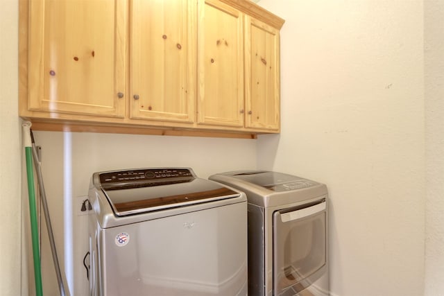 clothes washing area featuring cabinets and washing machine and clothes dryer