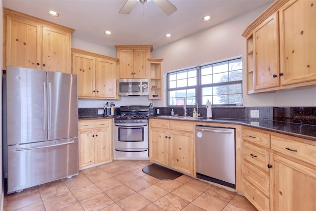 kitchen with stainless steel appliances, light brown cabinets, ceiling fan, light tile patterned floors, and dark stone counters