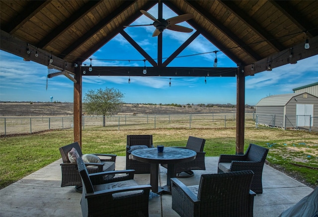 view of patio / terrace with a gazebo, a storage unit, a rural view, and ceiling fan