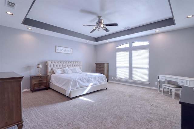 carpeted bedroom featuring a raised ceiling and ceiling fan