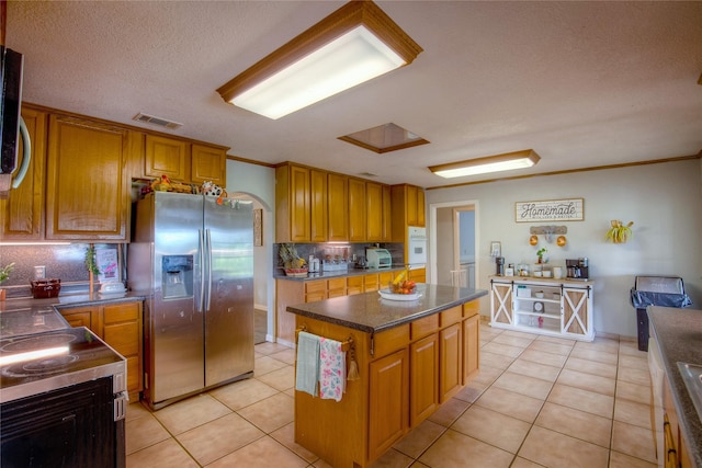 kitchen with decorative backsplash, light tile patterned flooring, a center island, and appliances with stainless steel finishes