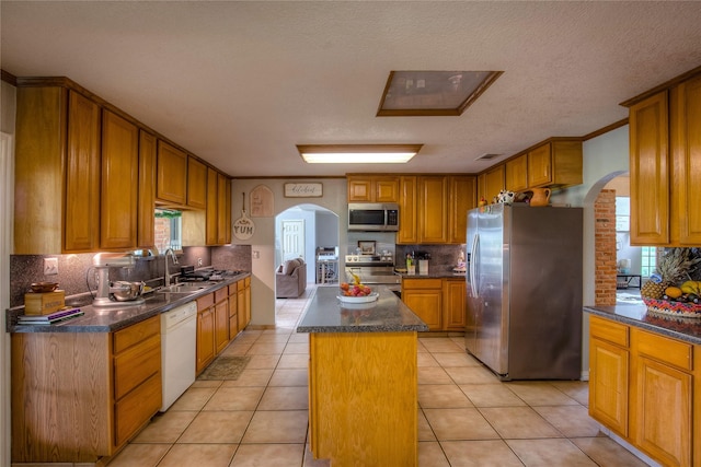 kitchen with stainless steel appliances, backsplash, a kitchen island, and light tile patterned floors