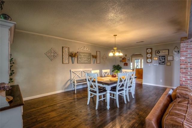 dining room featuring dark hardwood / wood-style flooring, a textured ceiling, crown molding, and a chandelier