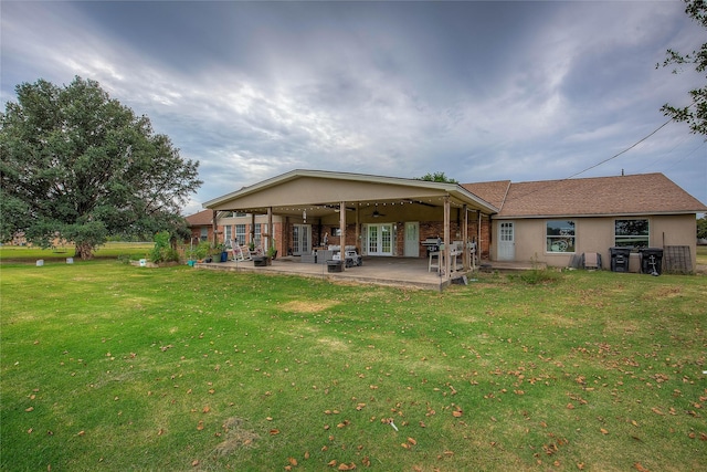 rear view of property with a lawn, french doors, a patio area, and ceiling fan