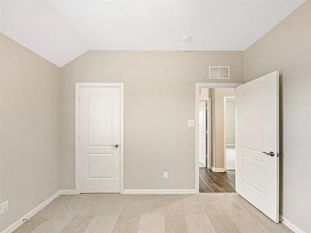 carpeted spare room featuring lofted ceiling