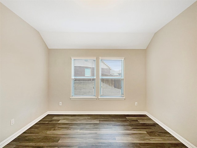 spare room featuring dark wood-type flooring and lofted ceiling