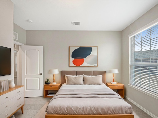 bedroom with light colored carpet and multiple windows