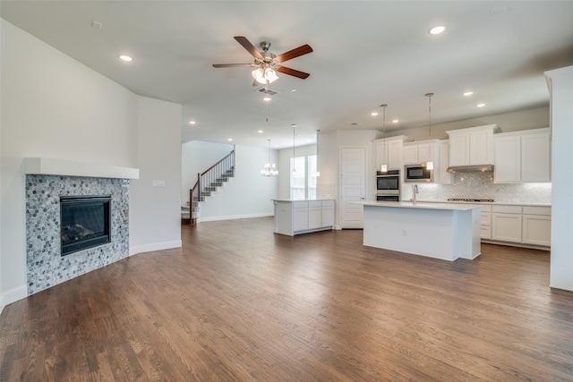 kitchen featuring white cabinets, a kitchen island with sink, appliances with stainless steel finishes, and pendant lighting