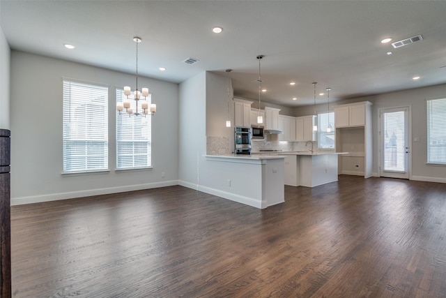 kitchen with white cabinets, dark hardwood / wood-style floors, a wealth of natural light, and hanging light fixtures