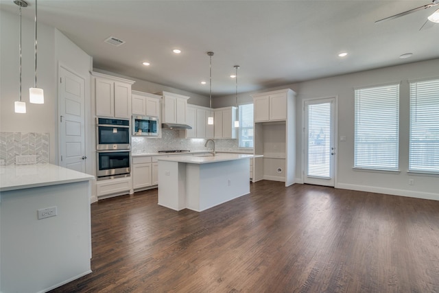 kitchen with white cabinets, hanging light fixtures, backsplash, and stainless steel appliances