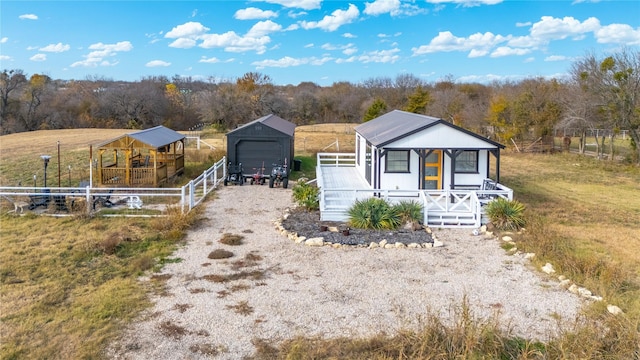 manufactured / mobile home featuring a porch, a rural view, and an outdoor structure