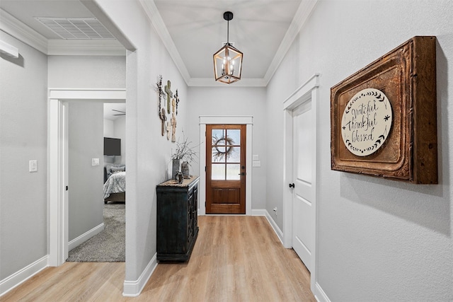 entrance foyer with a chandelier, crown molding, and light hardwood / wood-style flooring