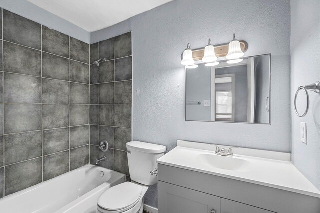 full bathroom featuring vanity, tiled shower / bath combo, and toilet