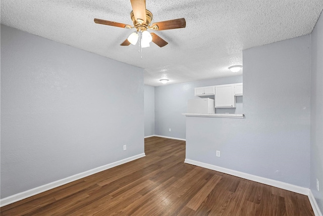 spare room with a textured ceiling, ceiling fan, and dark wood-type flooring