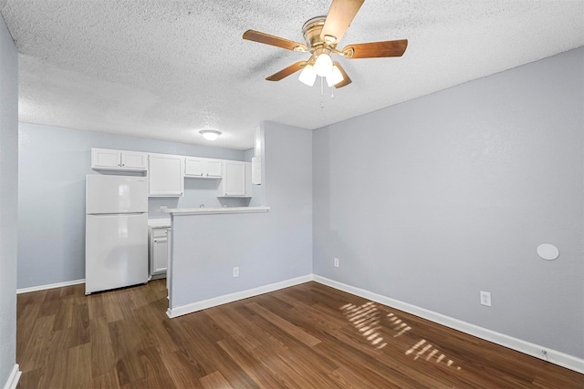 kitchen with white fridge, ceiling fan, dark wood-type flooring, a textured ceiling, and white cabinetry