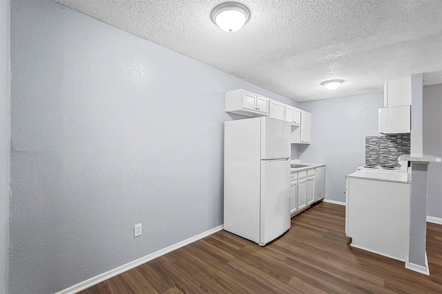 kitchen with a textured ceiling, dark hardwood / wood-style flooring, white fridge, and white cabinetry