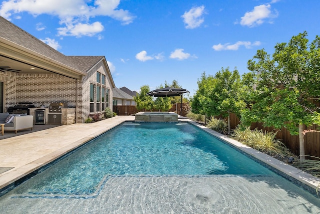 view of pool with a patio area, area for grilling, an in ground hot tub, and exterior kitchen