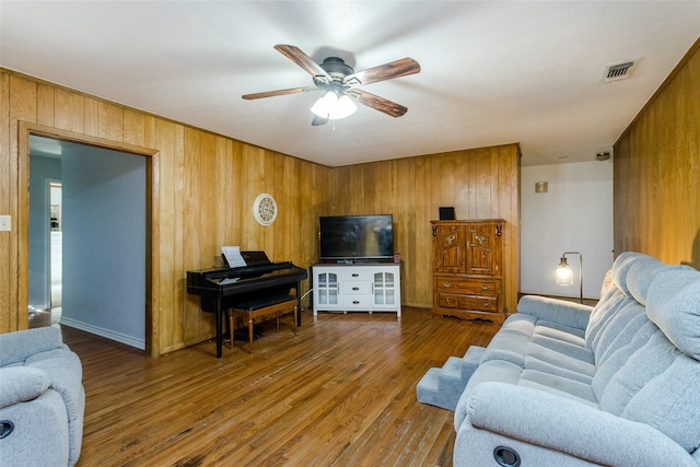 living room featuring hardwood / wood-style floors, wood walls, and ceiling fan