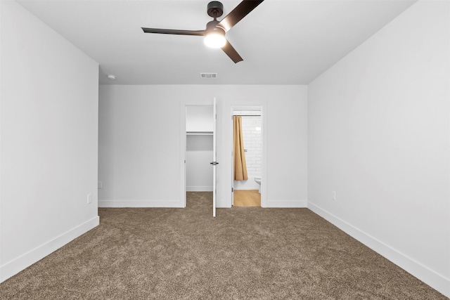 unfurnished bedroom featuring ensuite bathroom, carpet flooring, ceiling fan, a closet, and a walk in closet