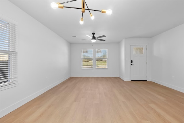 interior space with ceiling fan with notable chandelier and light hardwood / wood-style floors