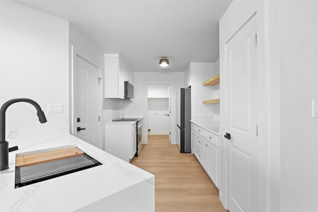 kitchen with stainless steel appliances, light stone countertops, and white cabinets