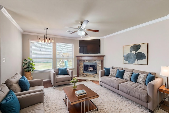 living room featuring ornamental molding, a stone fireplace, ceiling fan with notable chandelier, and light hardwood / wood-style flooring