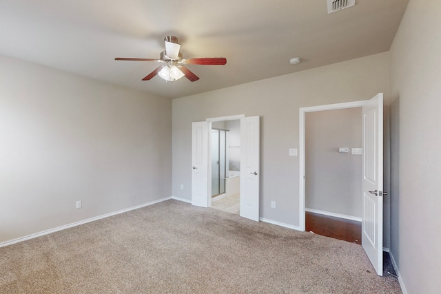 unfurnished bedroom with ceiling fan, ensuite bathroom, and light carpet