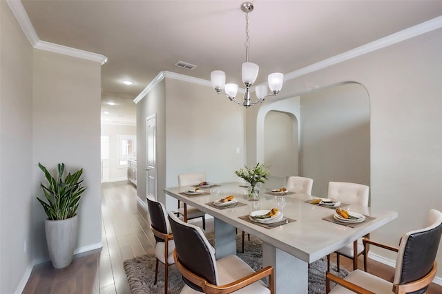 dining room with hardwood / wood-style flooring, ornamental molding, and a chandelier