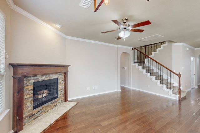 unfurnished living room featuring crown molding, a stone fireplace, and light wood-type flooring