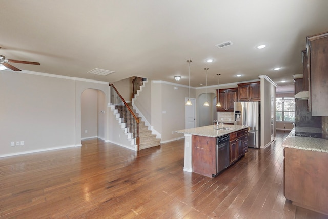 kitchen with a center island with sink, appliances with stainless steel finishes, dark hardwood / wood-style flooring, pendant lighting, and light stone countertops