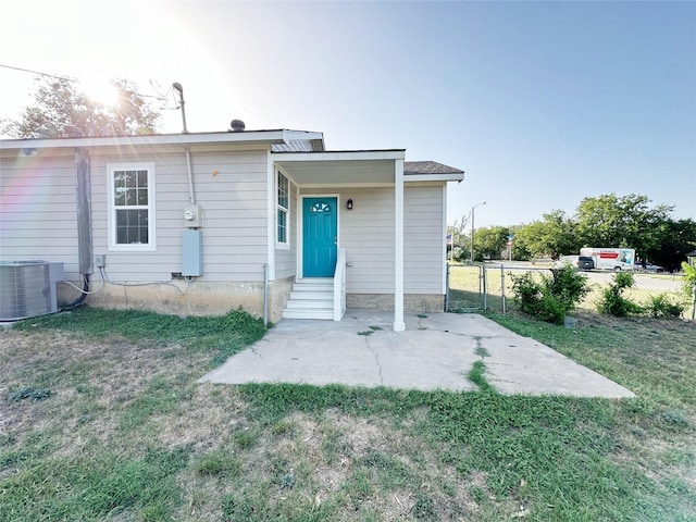 rear view of property with cooling unit, a patio area, and a yard