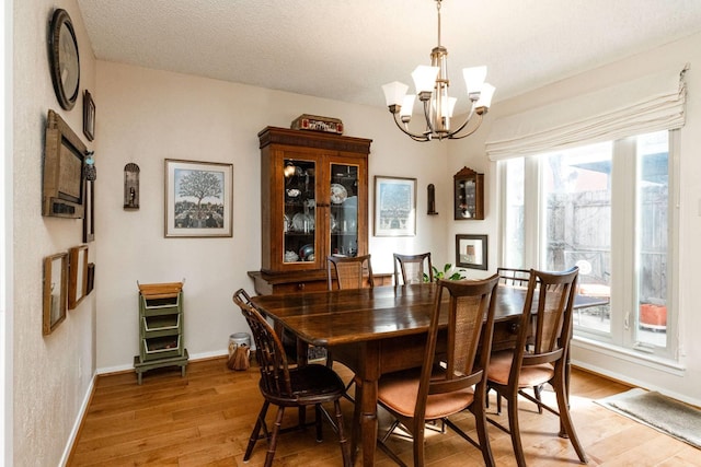 dining area with hardwood / wood-style flooring, a textured ceiling, and a notable chandelier