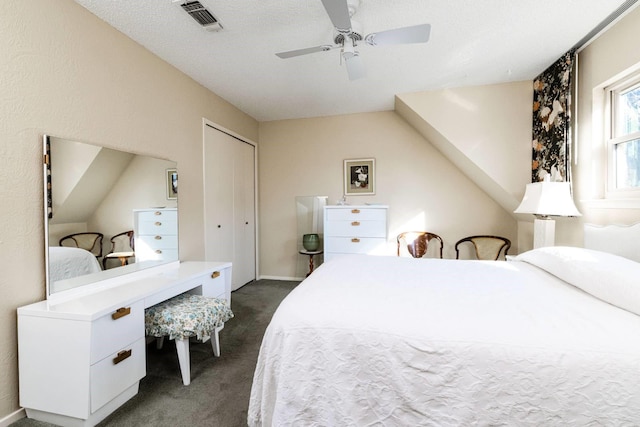 bedroom featuring ceiling fan, a closet, a textured ceiling, and dark carpet