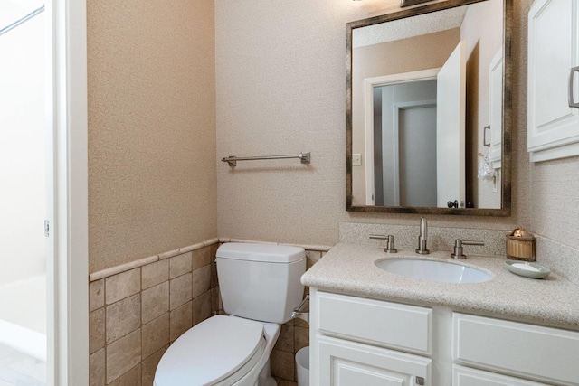 bathroom with tile walls, toilet, and vanity