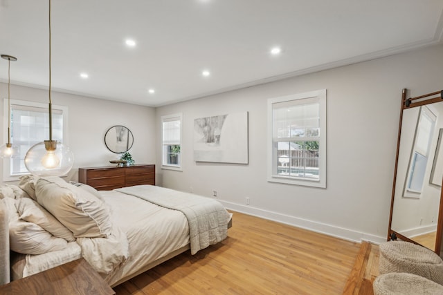 bedroom with light hardwood / wood-style floors, crown molding, and a barn door