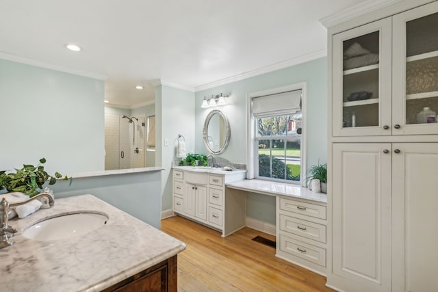 bathroom featuring ornamental molding, an enclosed shower, vanity, and hardwood / wood-style flooring