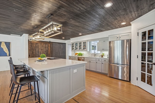 kitchen featuring stainless steel appliances, decorative light fixtures, a center island, a barn door, and gray cabinetry