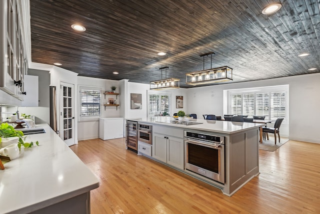 kitchen with hanging light fixtures, oven, a kitchen island, gray cabinetry, and wooden ceiling