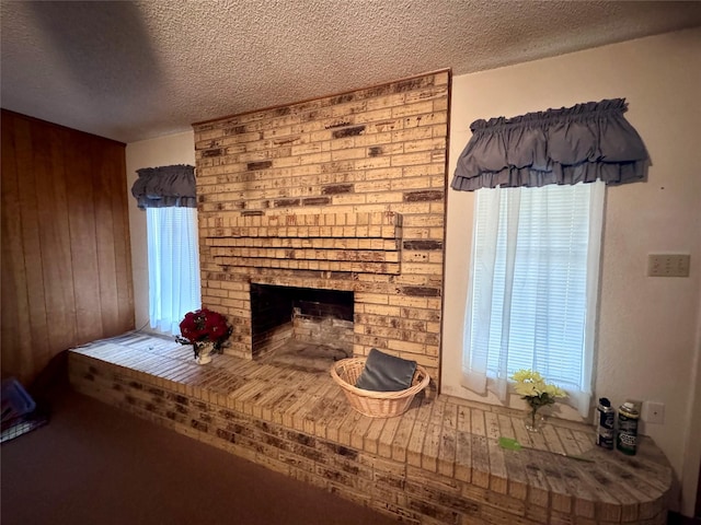 living room featuring a fireplace, a textured ceiling, and wood walls