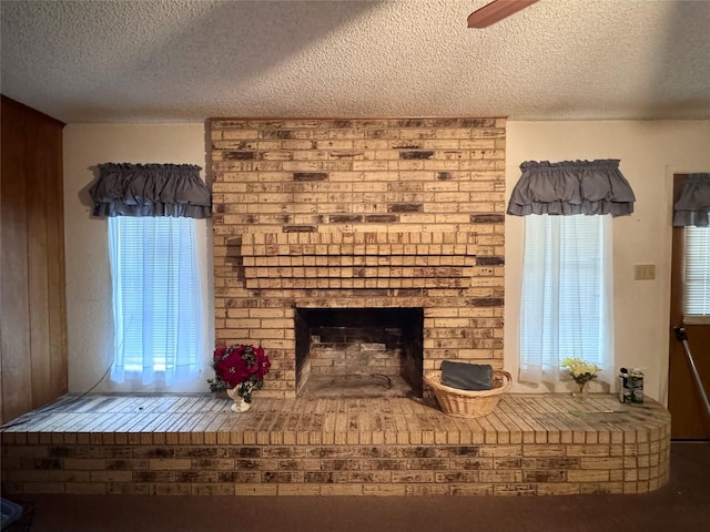 unfurnished room with a brick fireplace, a textured ceiling, and ceiling fan