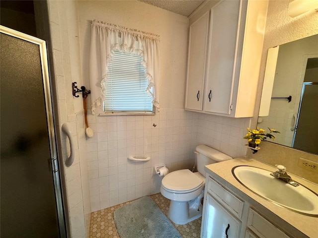 bathroom with toilet, walk in shower, tile patterned floors, vanity, and tile walls