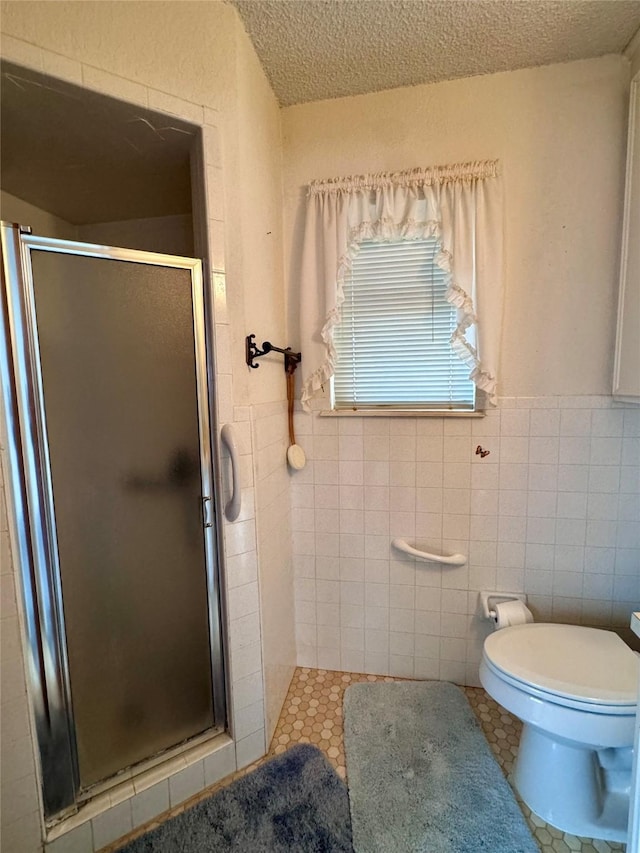 bathroom with toilet, walk in shower, a textured ceiling, and tile walls