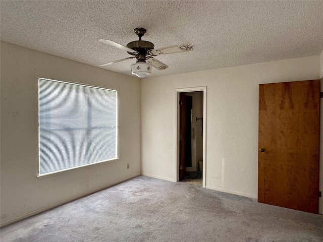 unfurnished room featuring ceiling fan, light colored carpet, and a textured ceiling