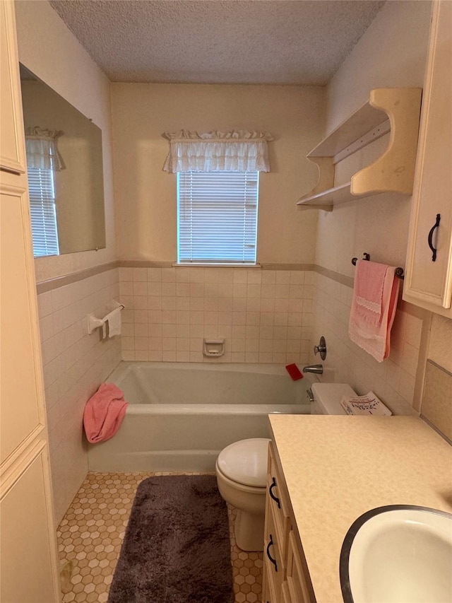 bathroom with toilet, vanity, tile walls, and a textured ceiling