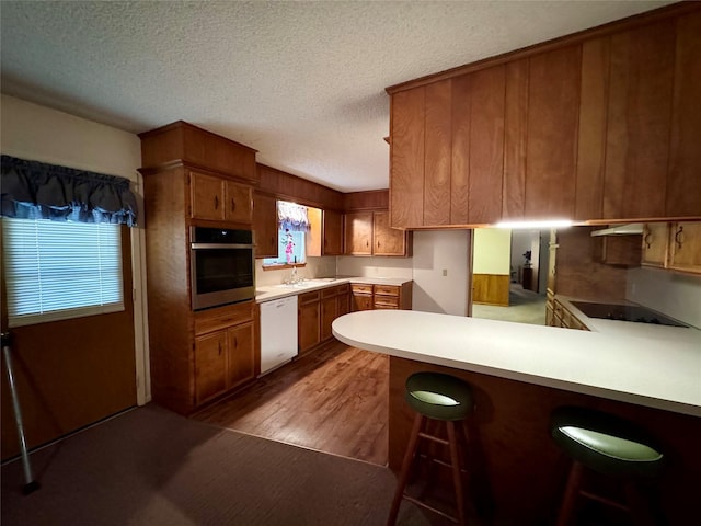 kitchen featuring dishwasher, a breakfast bar area, kitchen peninsula, a wealth of natural light, and oven