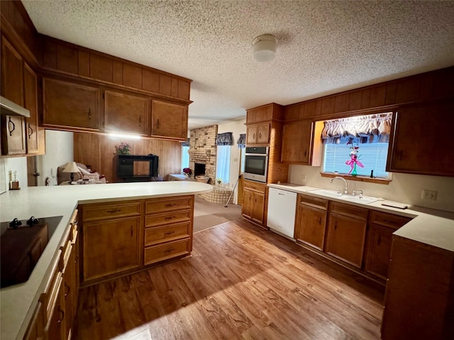 kitchen with sink, oven, light hardwood / wood-style floors, kitchen peninsula, and white dishwasher