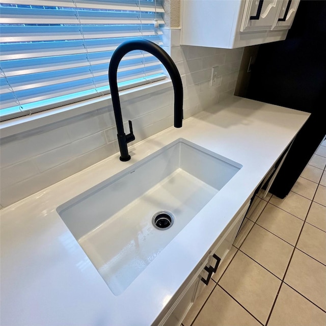 details featuring sink, white cabinetry, and backsplash