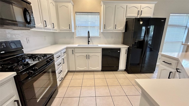 kitchen with light tile patterned floors, black appliances, backsplash, white cabinets, and sink