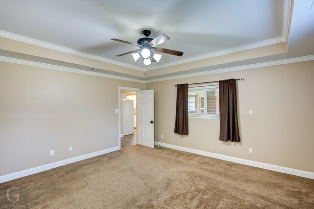 carpeted spare room featuring ornamental molding, ceiling fan, and a tray ceiling