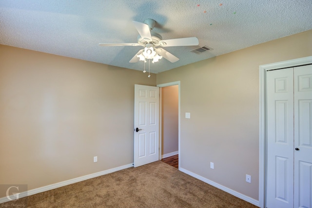 unfurnished bedroom featuring carpet flooring, a closet, ceiling fan, and a textured ceiling